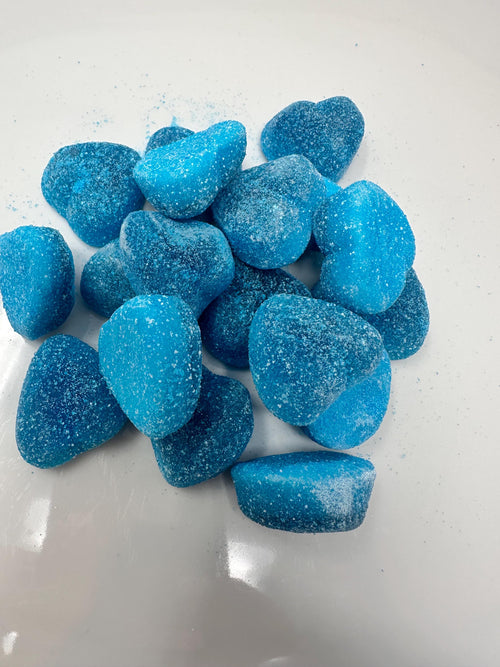Small pile of sugar-coated blue heart gummies resting on a white surface in natural light.