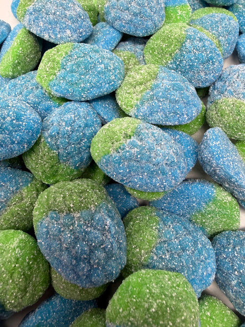 A close-up of larger, rounder gummy pieces with heavy, visibly sparkling sugar crystals catching the light across their blue and green surfaces.